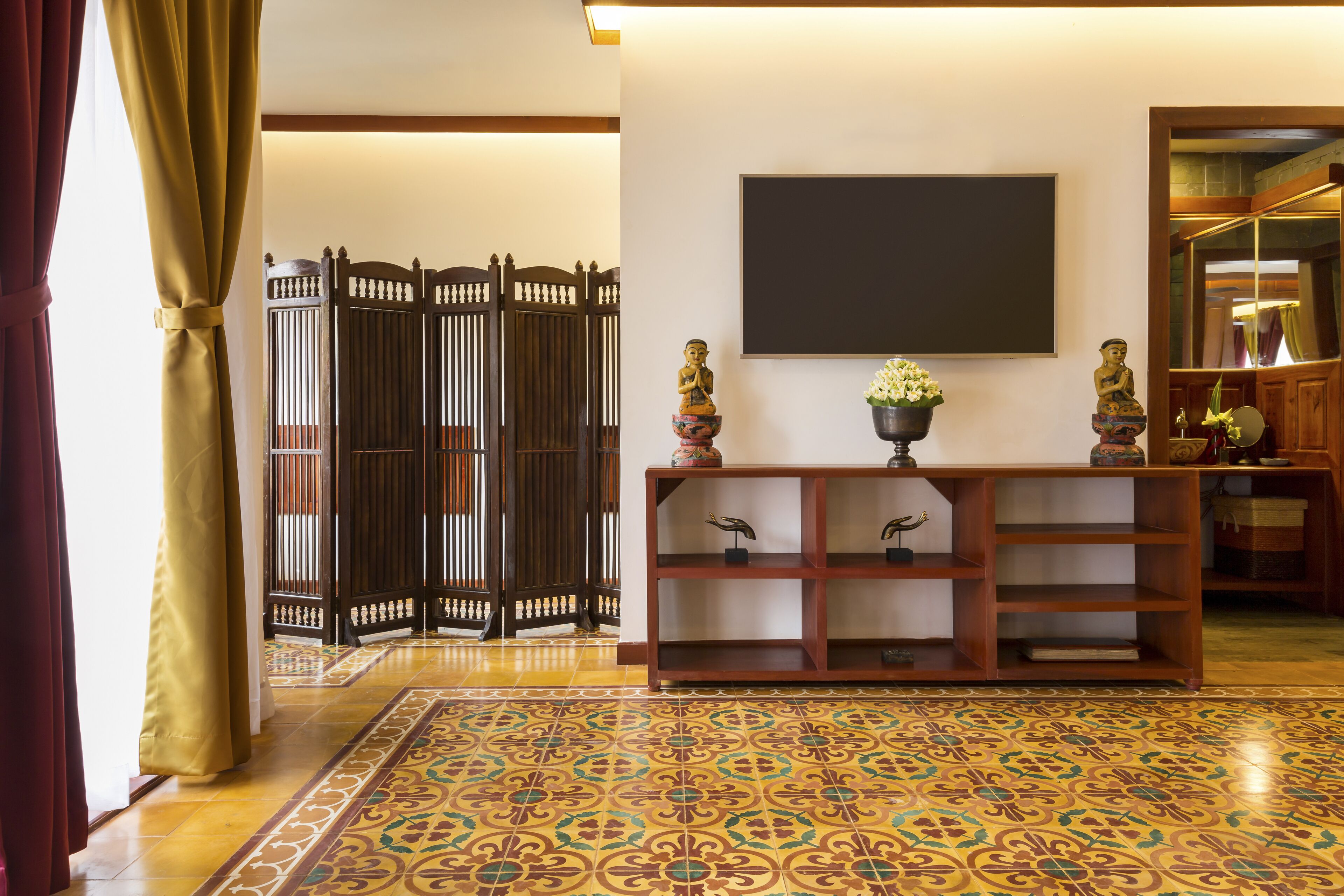 A traditional interior with a tatami mat floor, a wooden console table with decorative items, and a sliding door with a decorative screen.