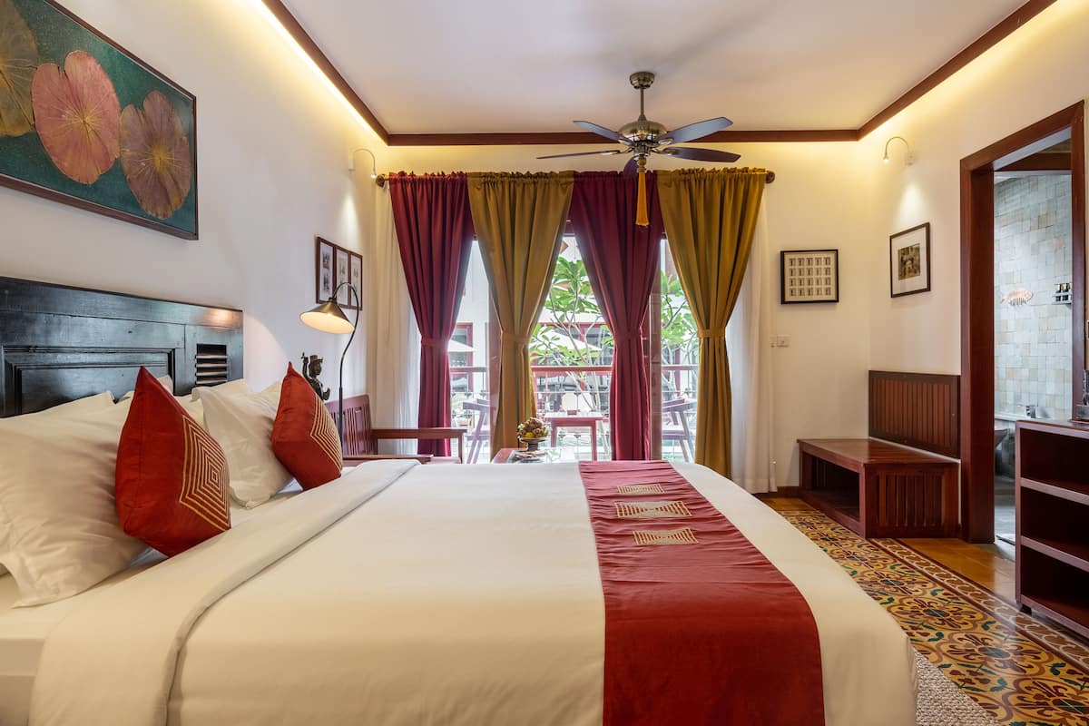 Ein Hotelzimmer mit einem großen Bett, einem Deckenventilator und Blick ins Freie.