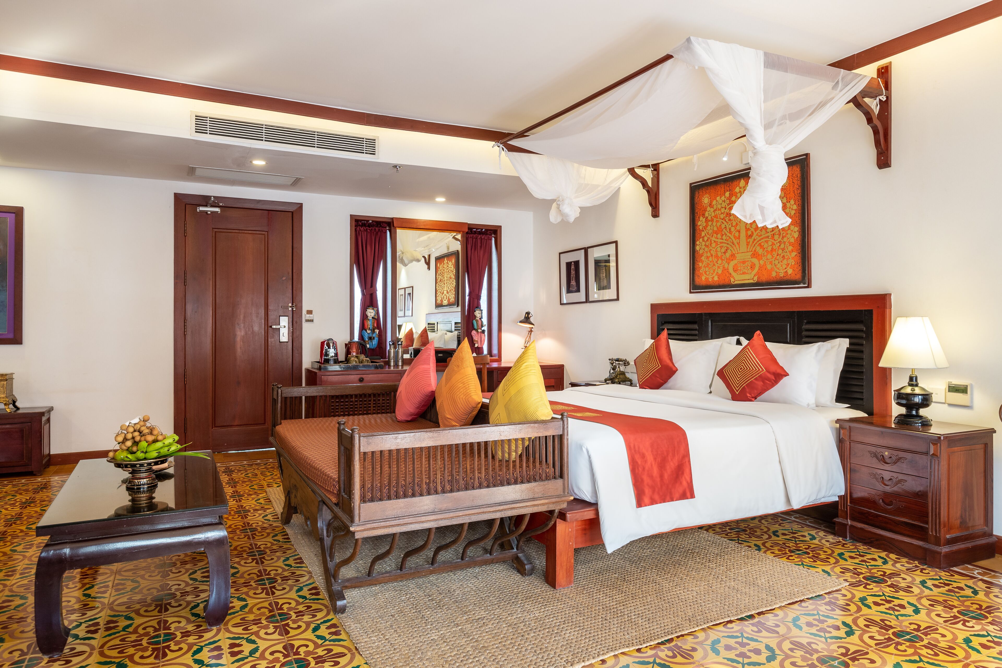 A hotel room with a bed, bedside table, nightstand, and a decorative mirror.