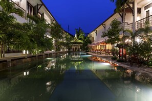 A serene pool area with a clear reflection, surrounded by lush greenery and traditional architecture. - Montra Nivesha Residence (Siem Reap)