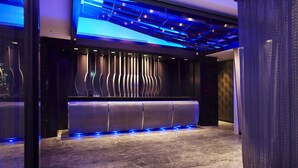 A modern reception area with a sleek reception desk, a patterned wall, and a ceiling with blue lighting. - The Tango Taipei ChangAn (Taipei)