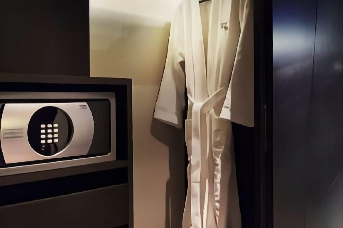 Una habitación con cerradura digital en la puerta, una bata blanca colgada en la pared y una puerta de madera oscura.