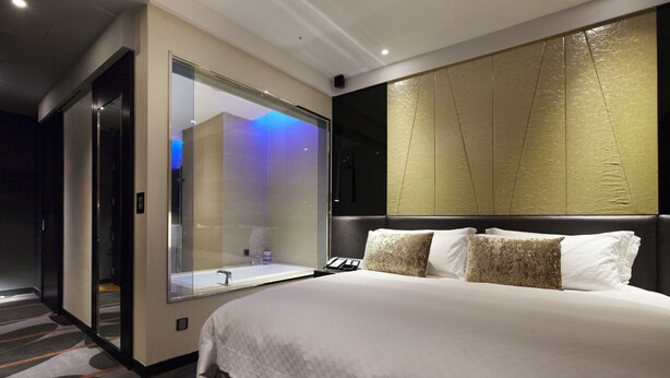 A modern hotel room with a large bed, a glass-enclosed bathroom, and a decorative wall panel. - The Tango Taipei ChangAn (Taipei)
