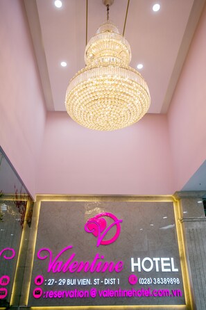 Señal de hotel con candelabro, letrero de neón e información de contacto.