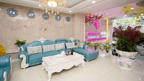 A hotel lobby with a blue sofa set, a white coffee table, and a chandelier.