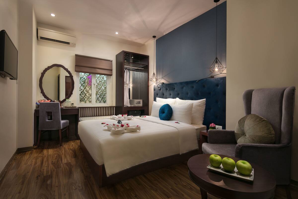Une chambre d’hôtel avec un grand lit, un bureau avec une chaise, une télévision, la climatisation, un miroir et une fenêtre donnant sur un beau paysage.