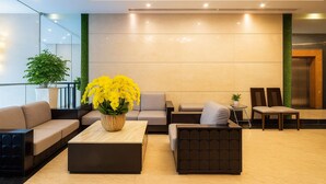 Een moderne lobby met een bank, fauteuils, een bijzettafeltje en een potplant.