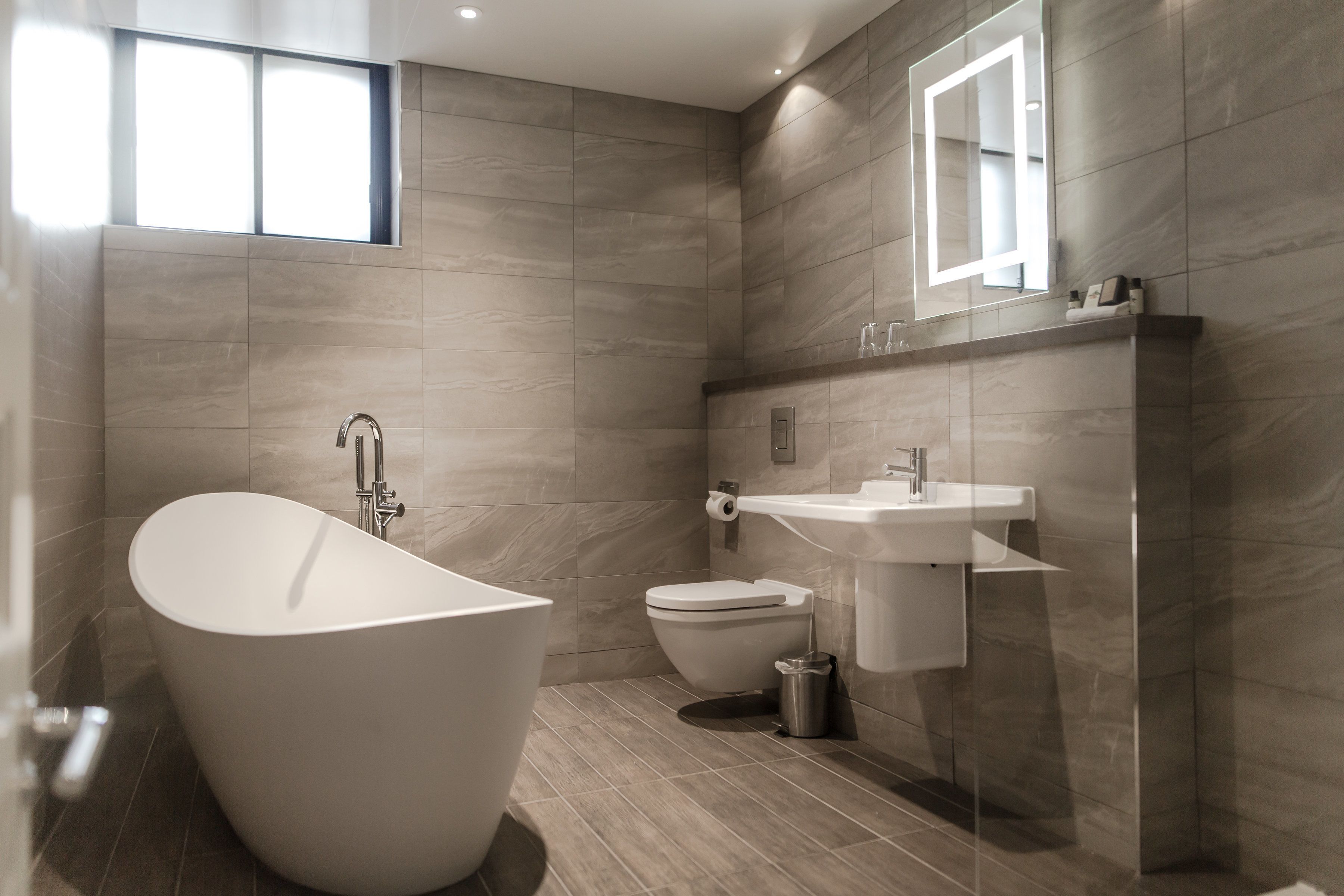 Un bagno moderno con una vasca da bagno indipendente, un water e un lavabo con uno specchio sopra.