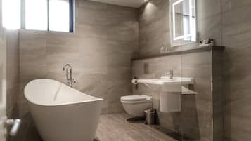 Un bagno moderno con una vasca da bagno indipendente, un water e un lavabo con uno specchio sopra.
