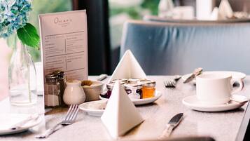 A restaurant table set with a menu, a glass vase with flowers, and various condiments.