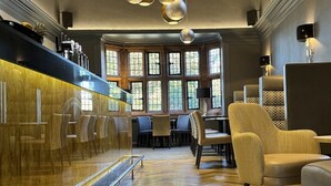 A modern hotel lobby with a glass partition, seating area, and a view of the outdoors through large windows. - Abbey House Hotel (Barrow-in-Furness)