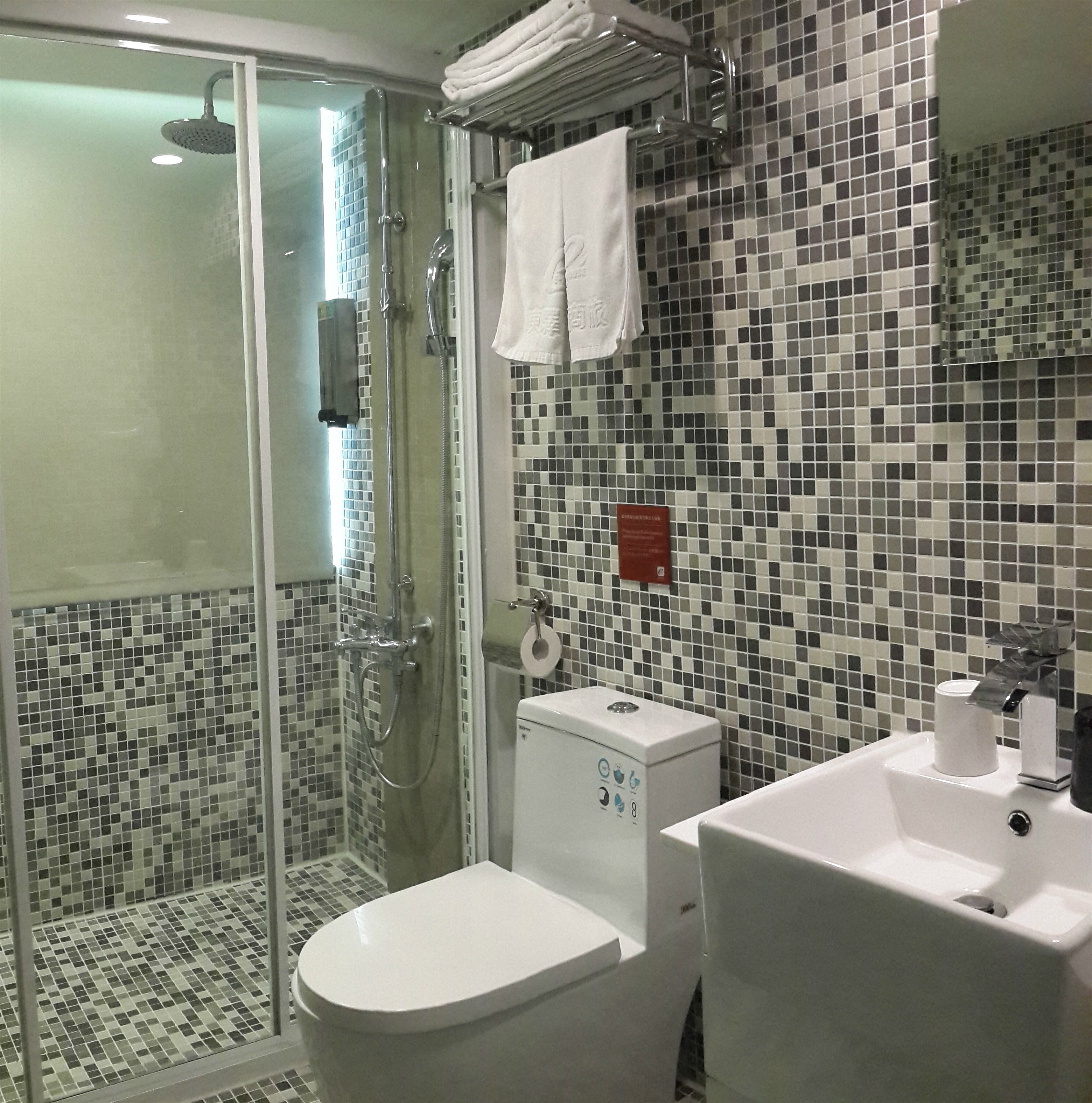 Une salle de bain avec une douche à parois de verre, des toilettes et un lavabo.