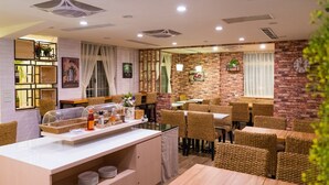 A restaurant with a brick wall, wicker chairs, and a buffet area. - E House Hotel (Taipei)
