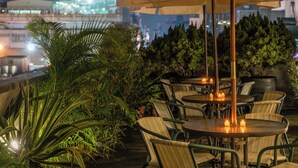An outdoor seating area with round tables and chairs, a large umbrella, and candles. - E House Hotel (Taipei)