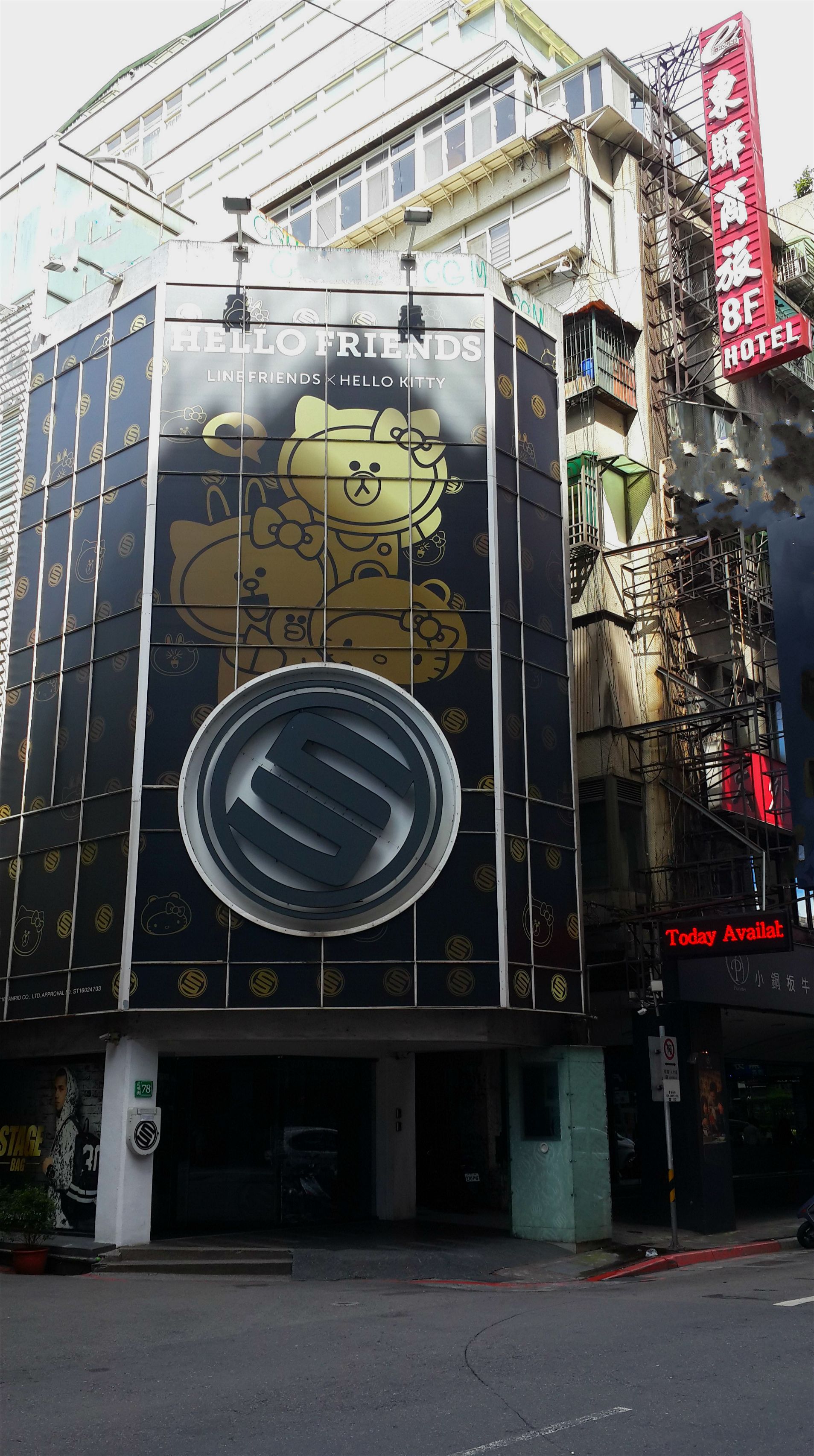 A building with a large advertisement for 'Hello Friends' featuring a Hello Kitty character. There is a sign for '8F Hotel' and a 'Today Available' sign.