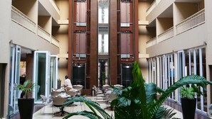 A multi-level atrium with a central open space, surrounded by balconies and glass doors leading to rooms. - Hotel Royal (Kinshasa)