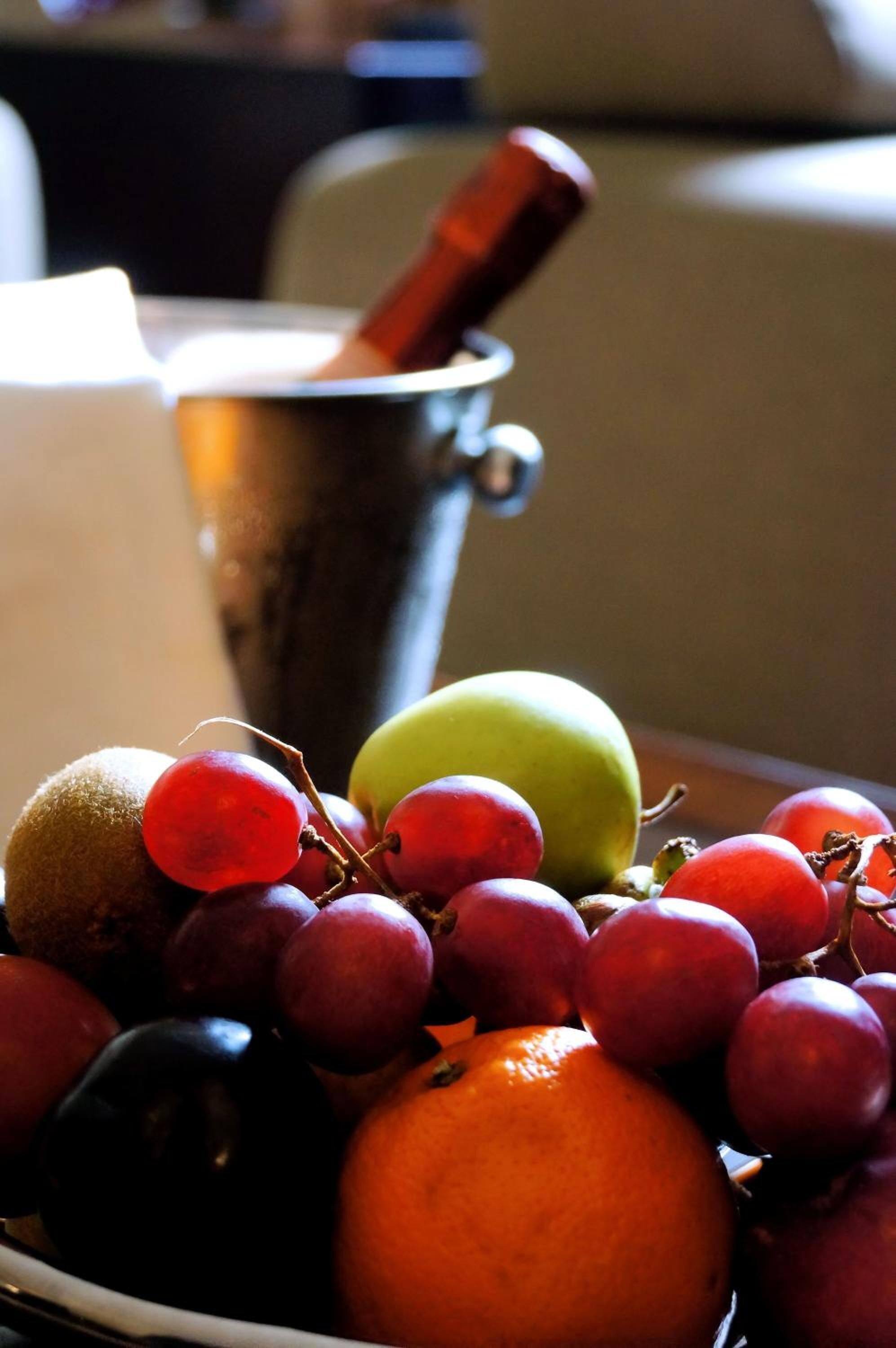 Een schaal met verschillende soorten fruit, waaronder druiven, een appel en een sinaasappel.