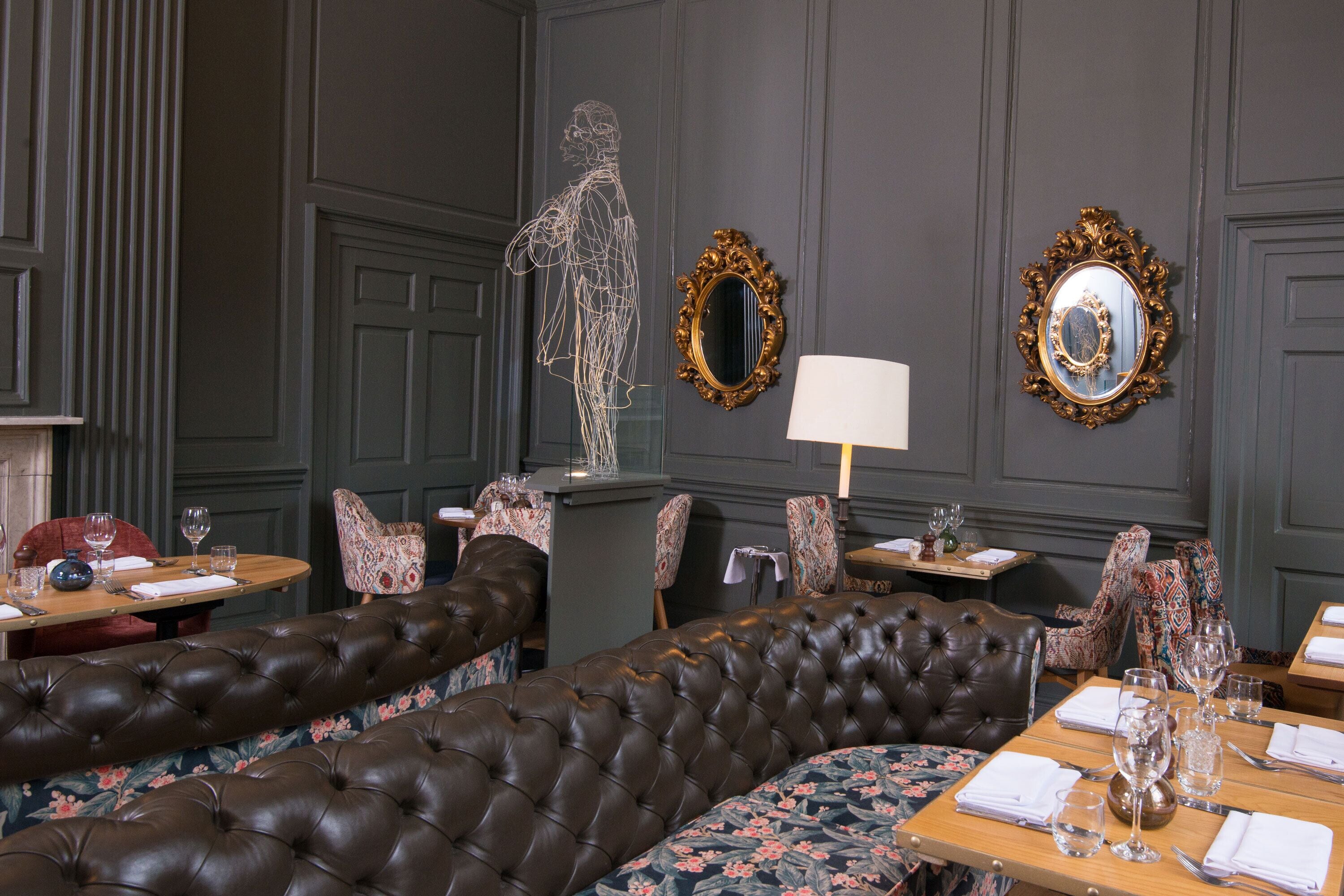 A dining area with a dark brown upholstered bench, ornate chairs, and a table set for dining.