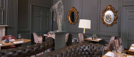 A dining area with a dark brown upholstered bench, ornate chairs, and a table set for dining.