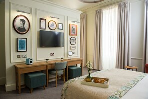 A hotel room with a bed, a desk with a computer, a television, and framed pictures on the wall. - Judges Lodgings York (York)
