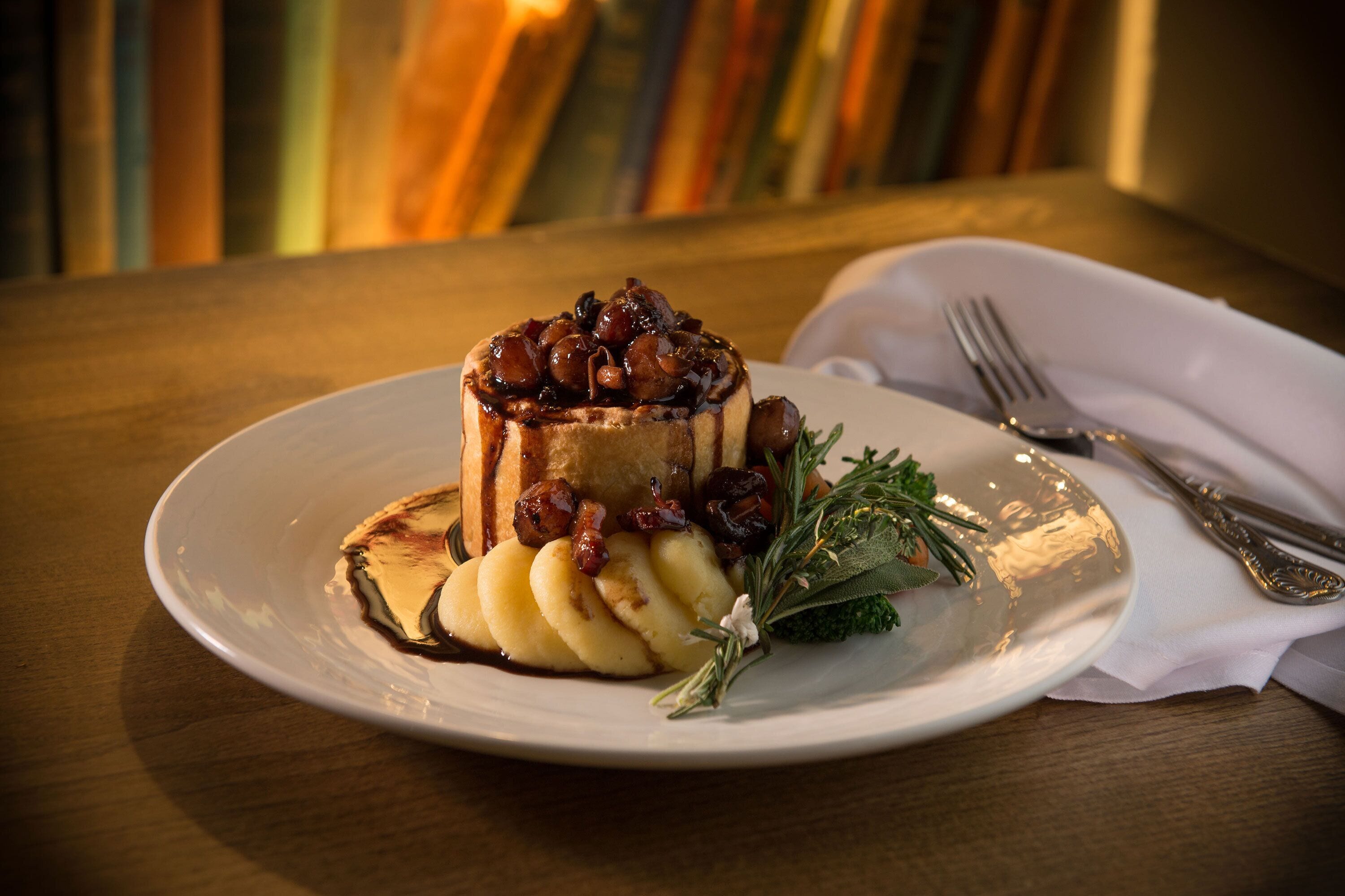 A dessert on a white plate with a fork and napkin on a wooden table.