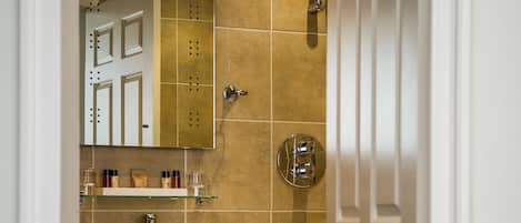 A bathroom with a sink, mirror, and shower.