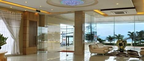 A modern lobby with a glass wall, a reception desk, and seating area.