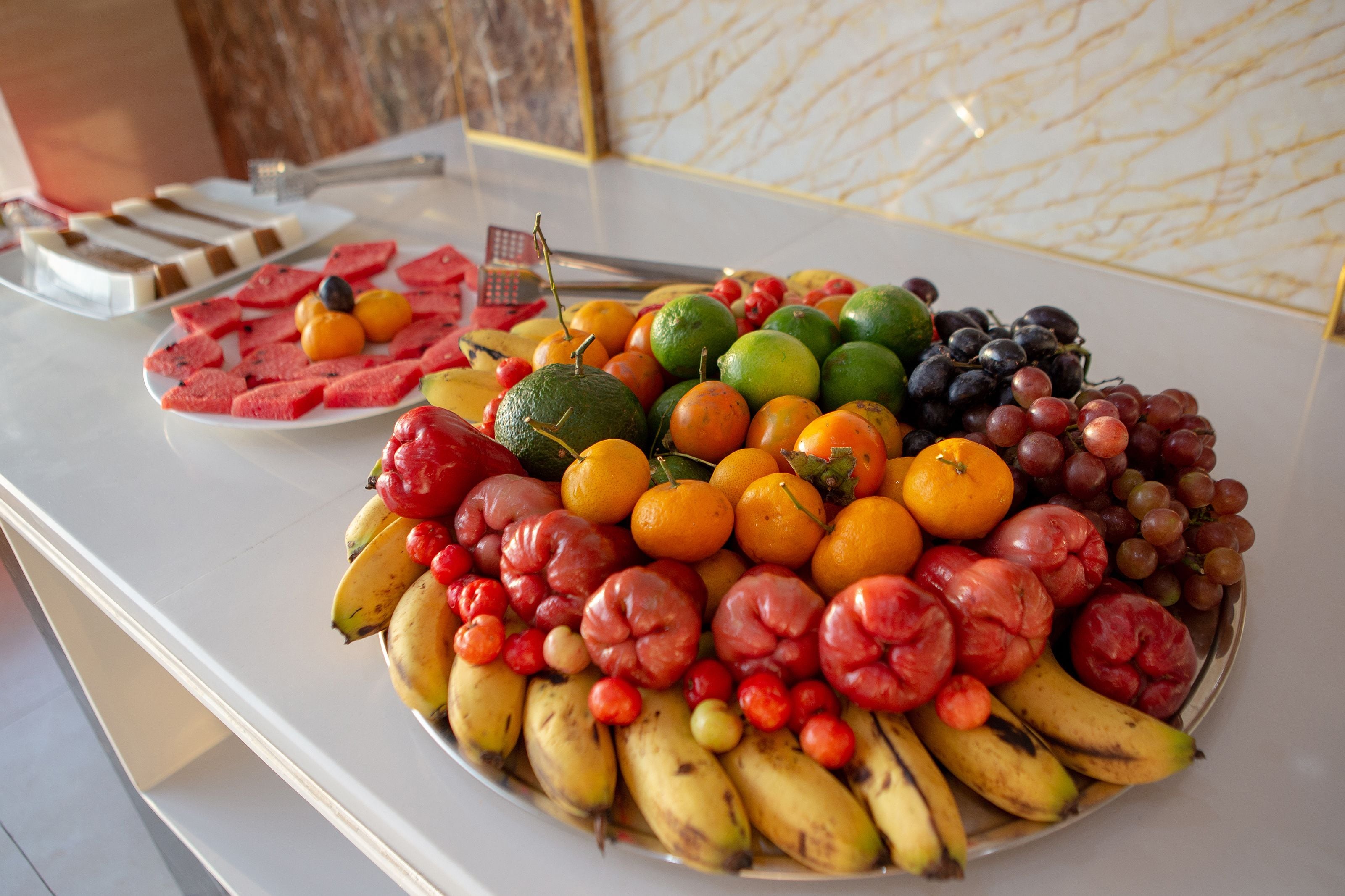 A buffet table with a variety of fruits and a plate of desserts.