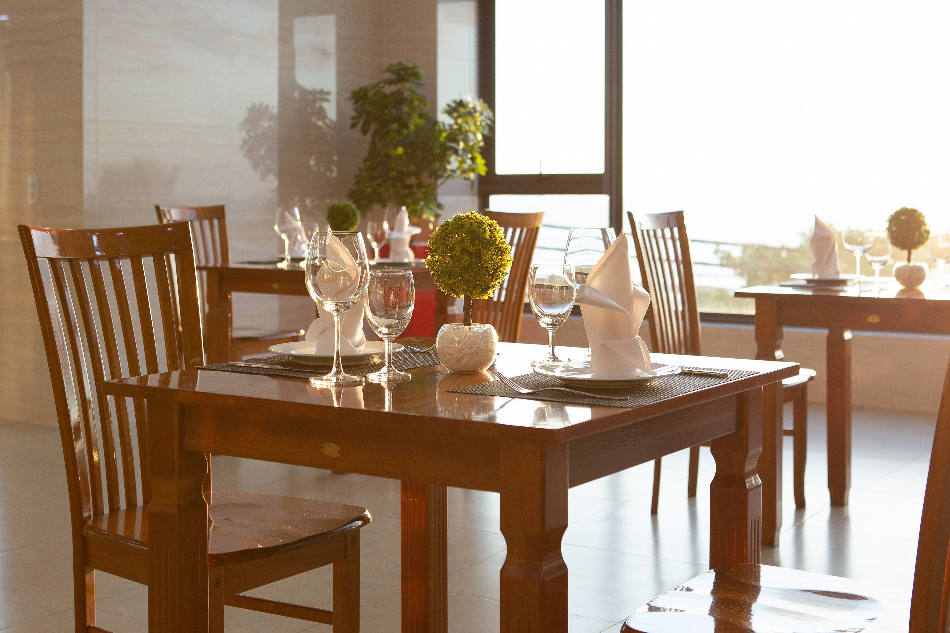 A dining table set with chairs, wine glasses, and a centerpiece.