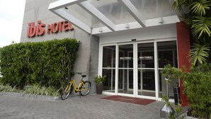 L’extérieur de l’hôtel Ibis présente un design moderne, avec un vélo garé devant et un jardin bien entretenu.