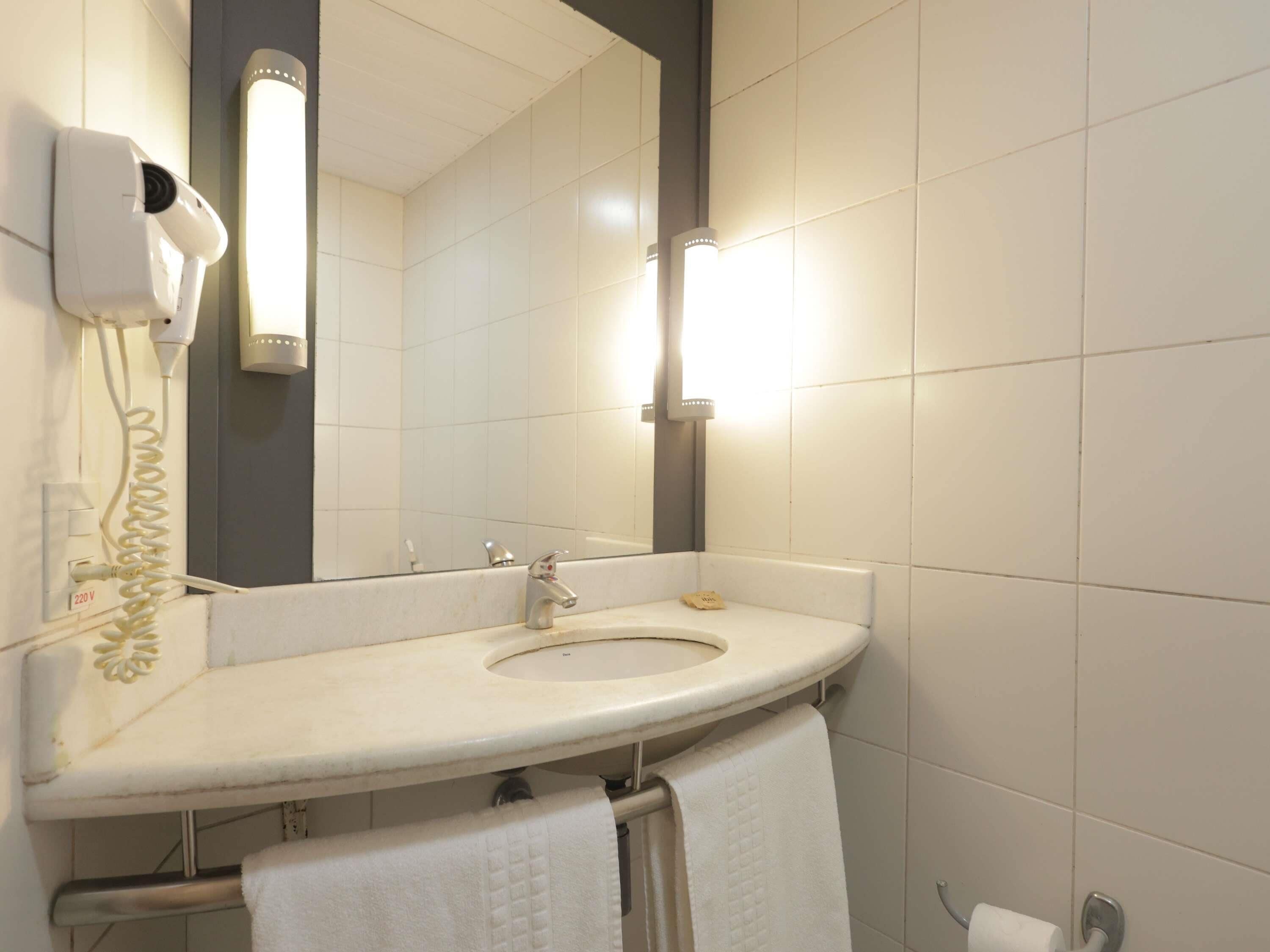 A bathroom with a sink, mirror, towel rack, and a hairdryer.