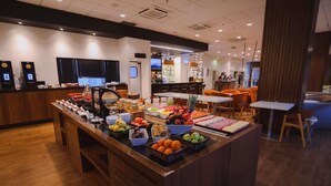 Un espace buffet proposant divers plats, un coin café et des tables où s’asseoir.