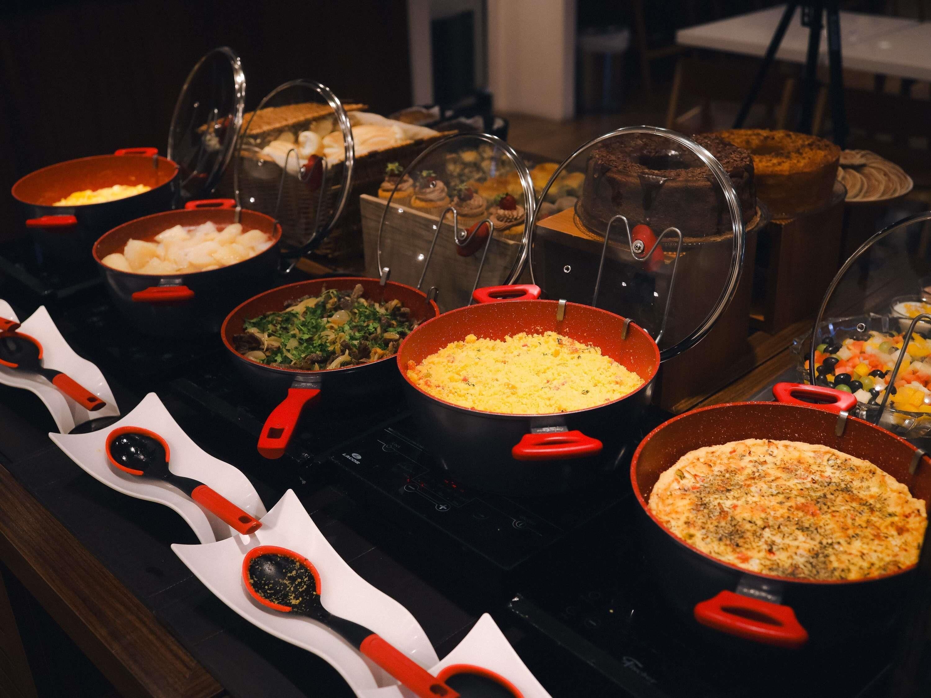 A buffet with various dishes in pots and pans, some covered with lids.