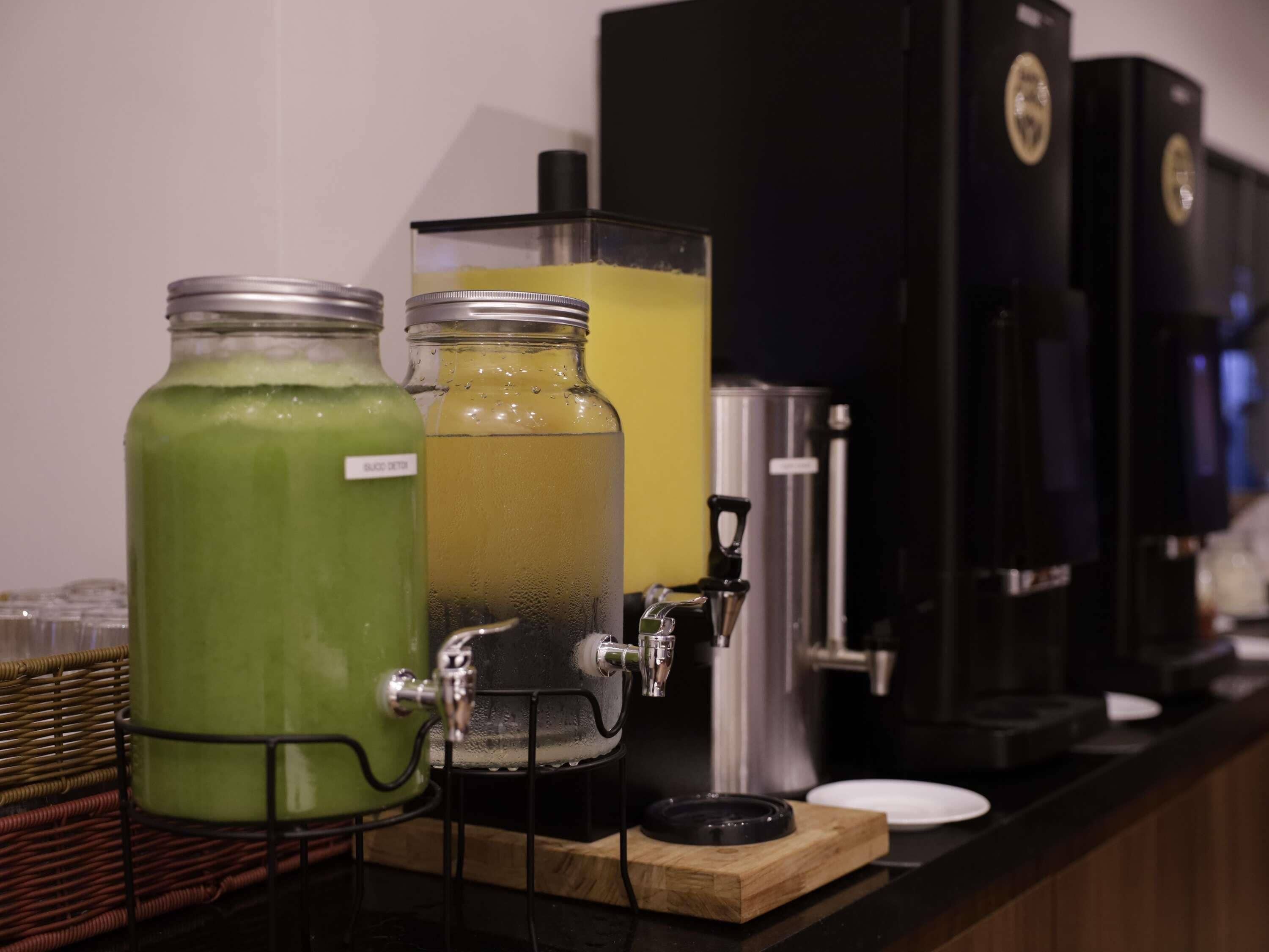 A beverage station with two large dispensers, one green and one yellow, and a coffee machine.