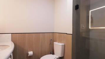 Un baño con inodoro, lavabo y zona de ducha.