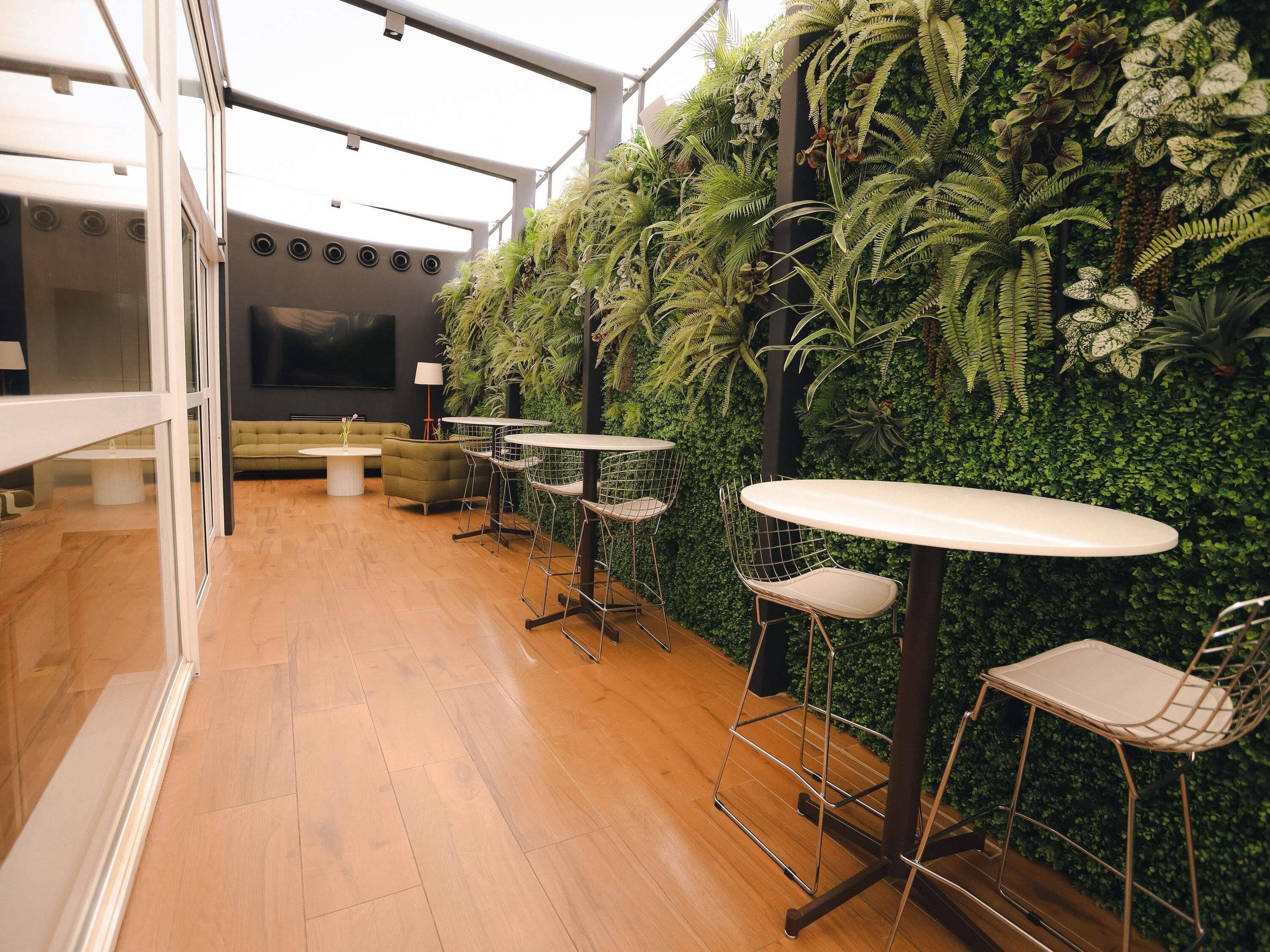 A modern interior with a green wall, wooden flooring, and metal chairs and tables.