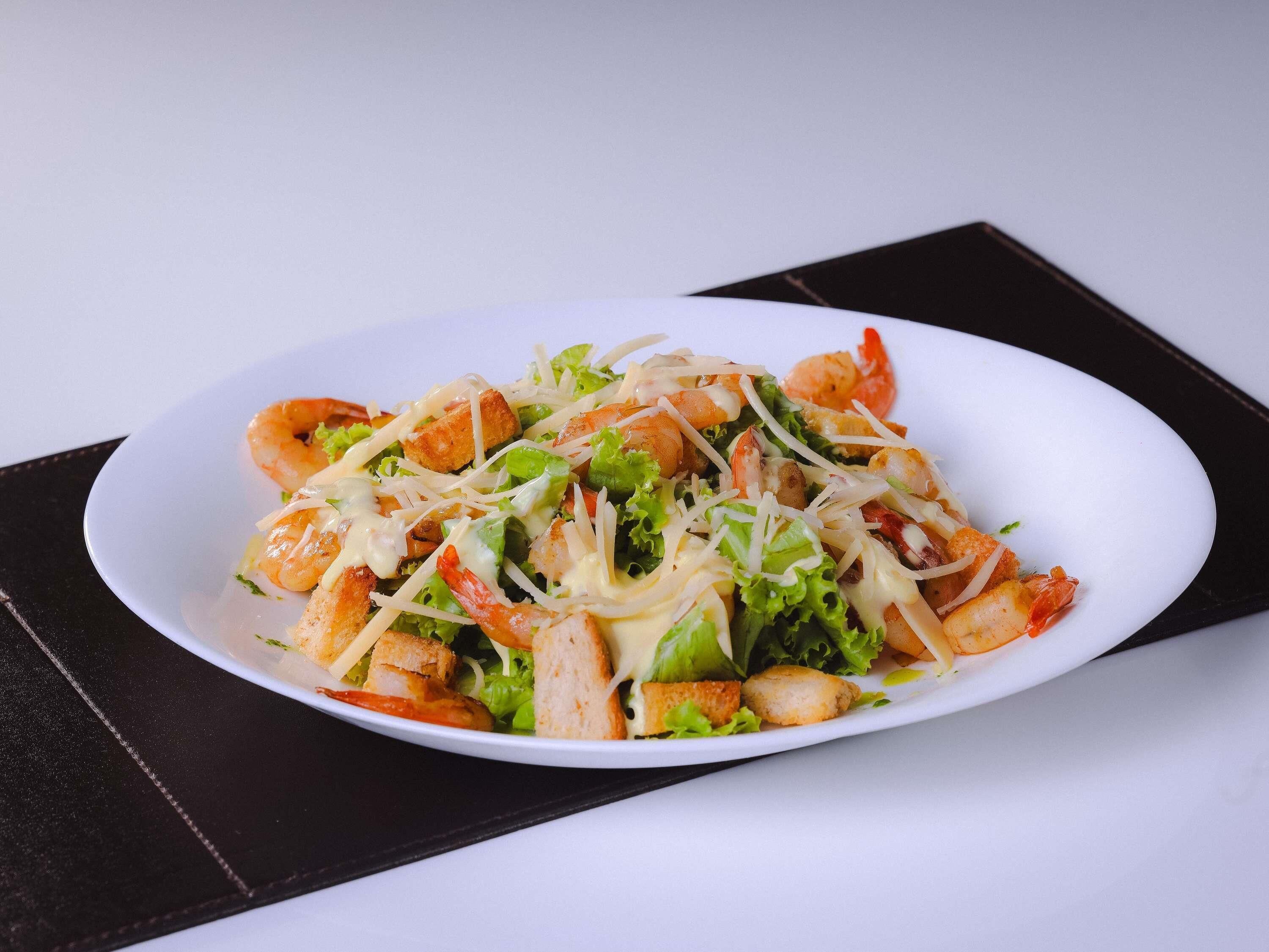 A white oval plate with a seafood salad on a black napkin.