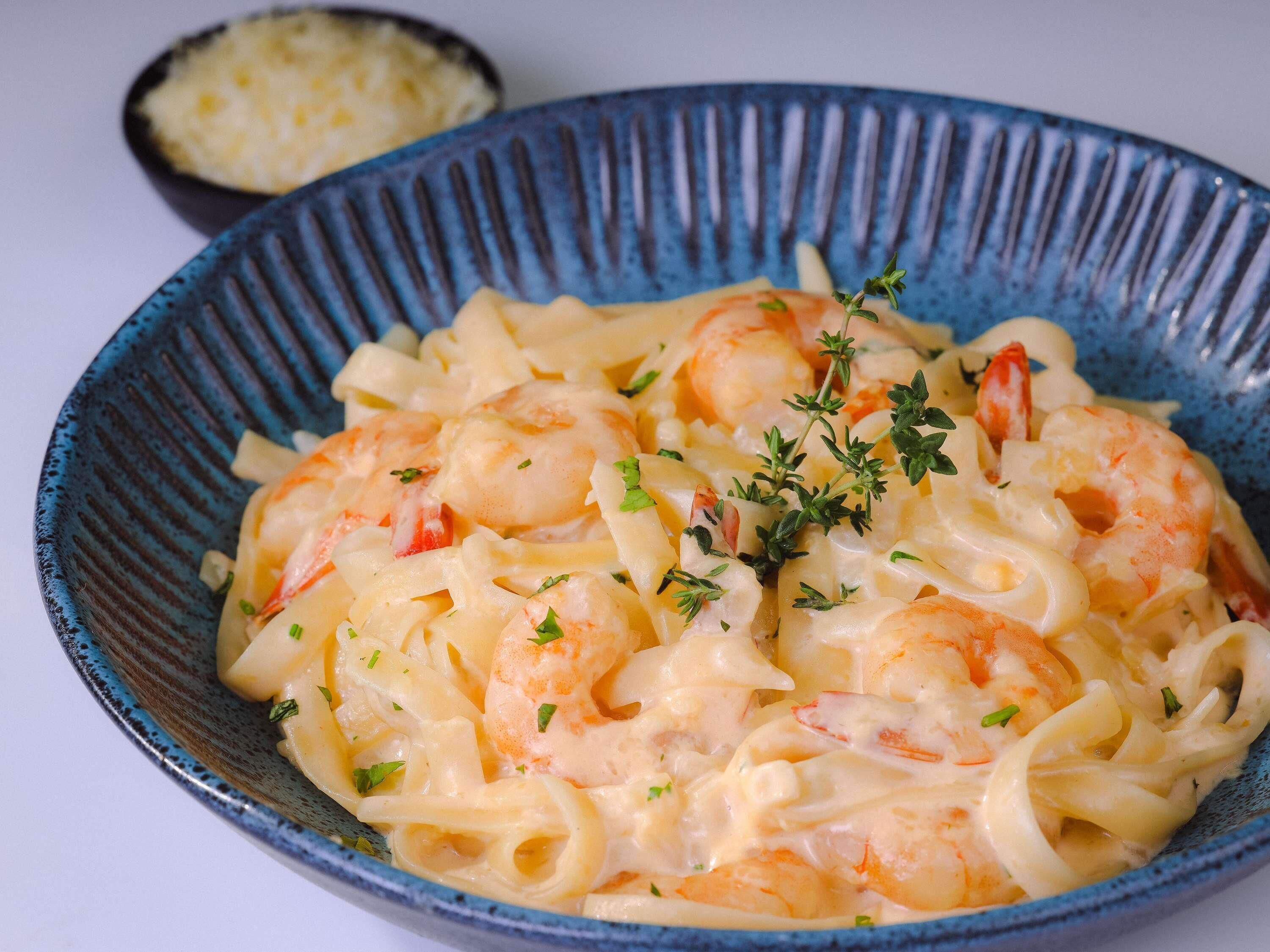 Un plato de pasta con camarones y hierbas.