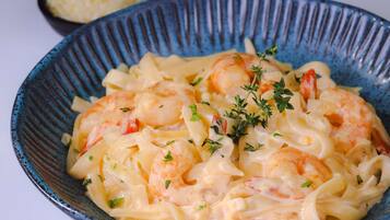 Un plato de pasta con camarones y hierbas.