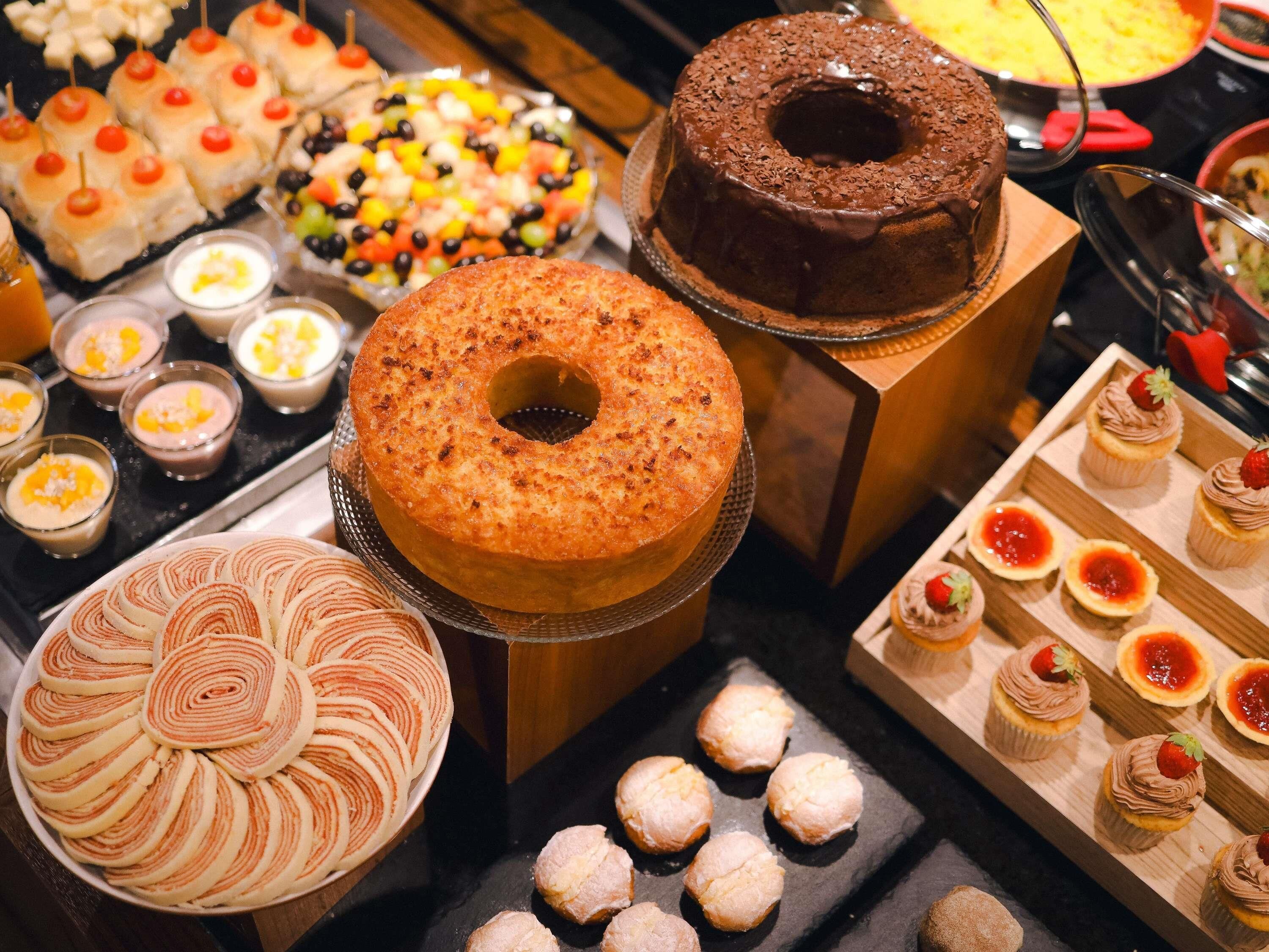 A variety of desserts including a chocolate cake, a fruit salad, and several small pastries.