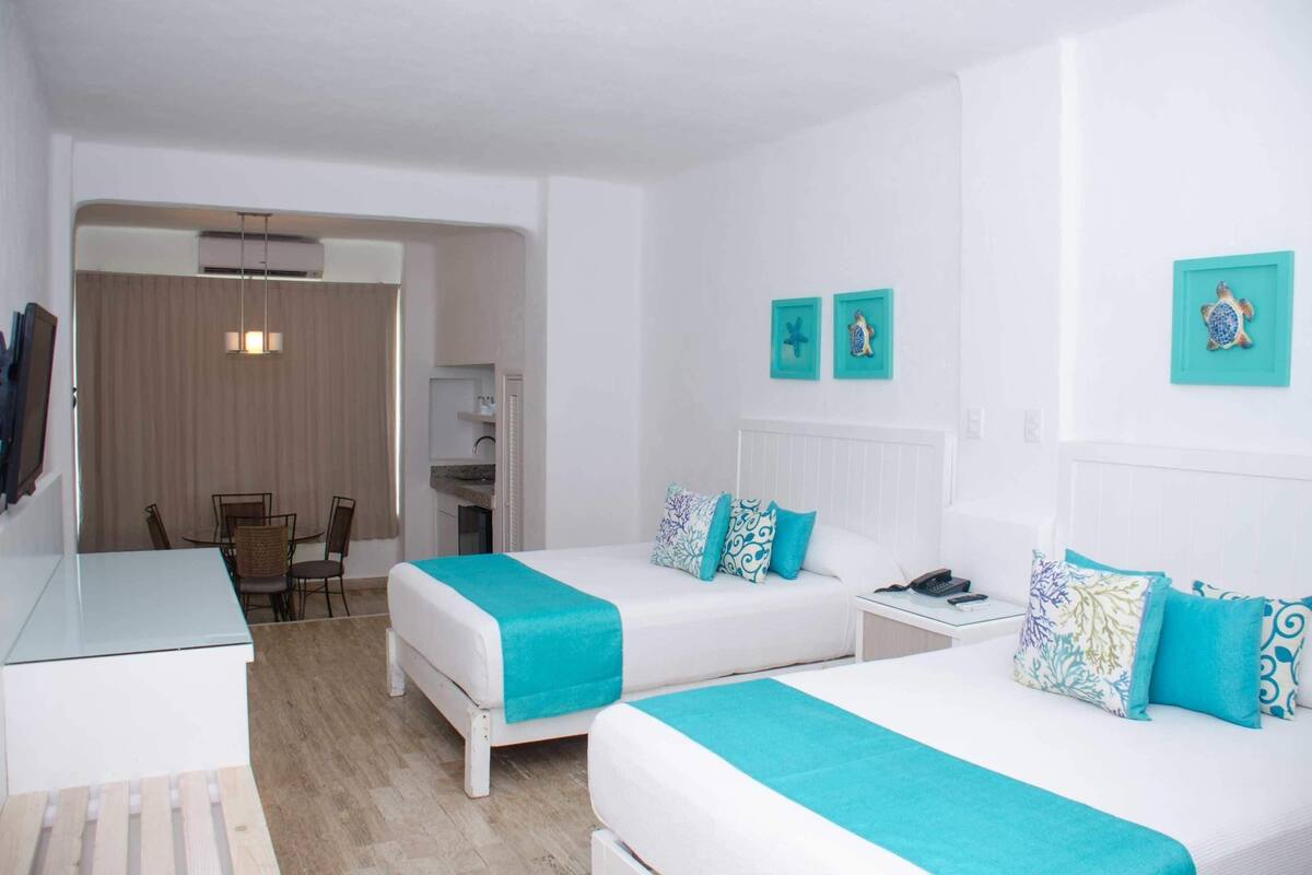 Habitación de hotel con dos camas, un escritorio, una silla y un comedor.