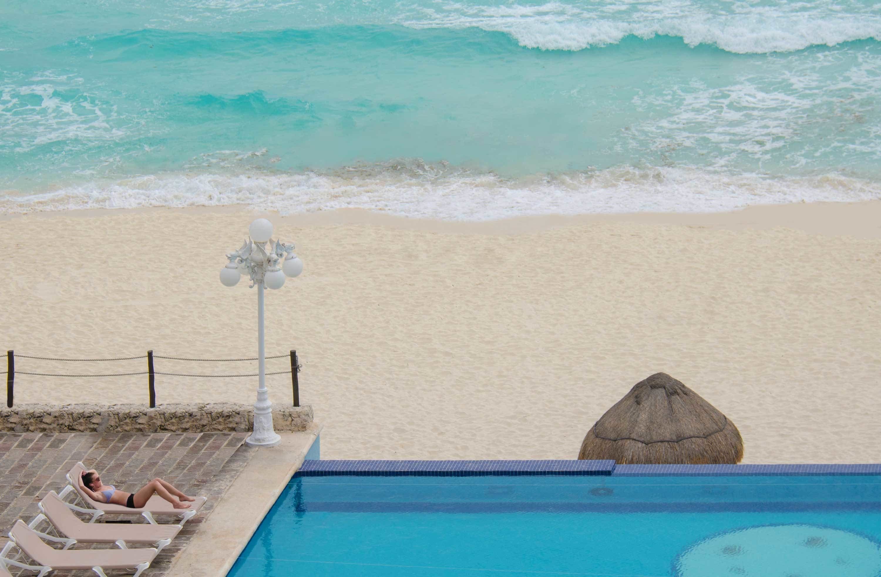 A poolside area with a view of the beach and ocean.