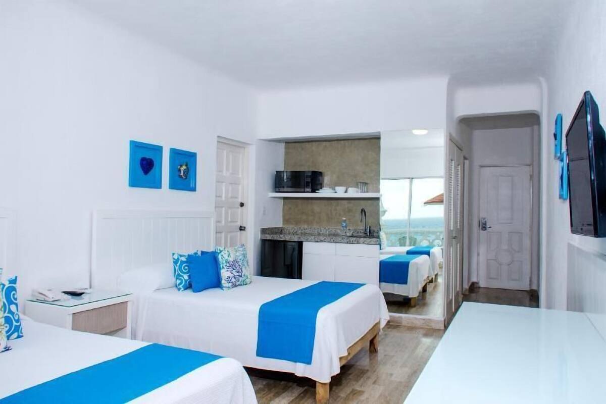 Una habitación de hotel con dos camas, una kitchenette y vistas.