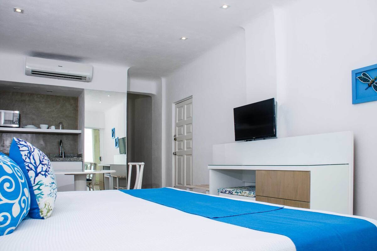 Una habitación de hotel moderna con cama, televisión, escritorio y baño.