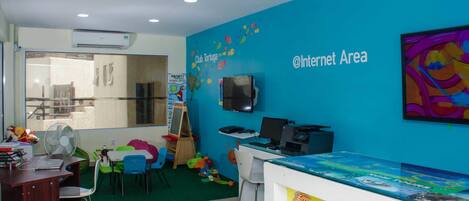 A children's play area with a blue wall, a TV, and a computer.