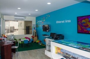 Zona de juegos infantiles con pared azul, televisor y ordenador.