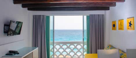 A room with a balcony, a bed, a desk, and a TV.