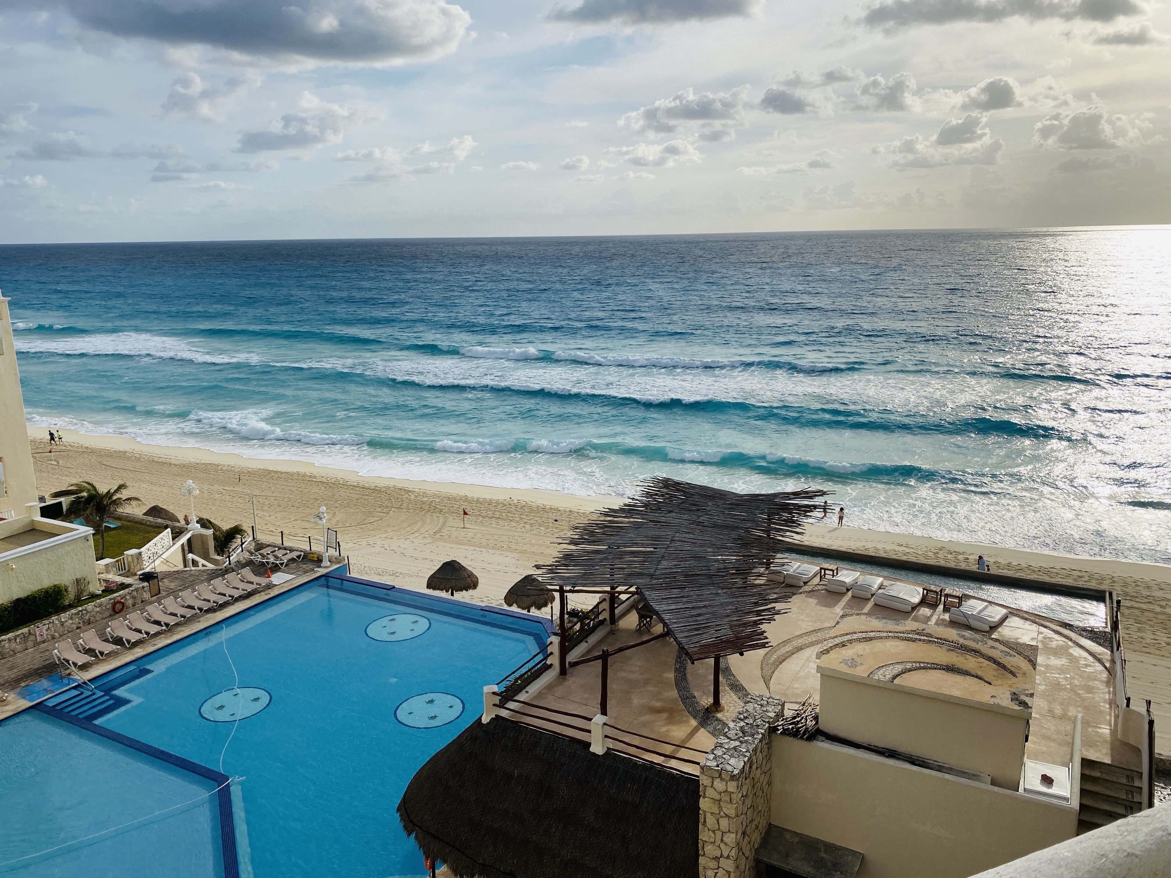 A pool area with a view of the beach and ocean.