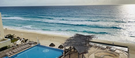 A pool area with a view of the beach and ocean.