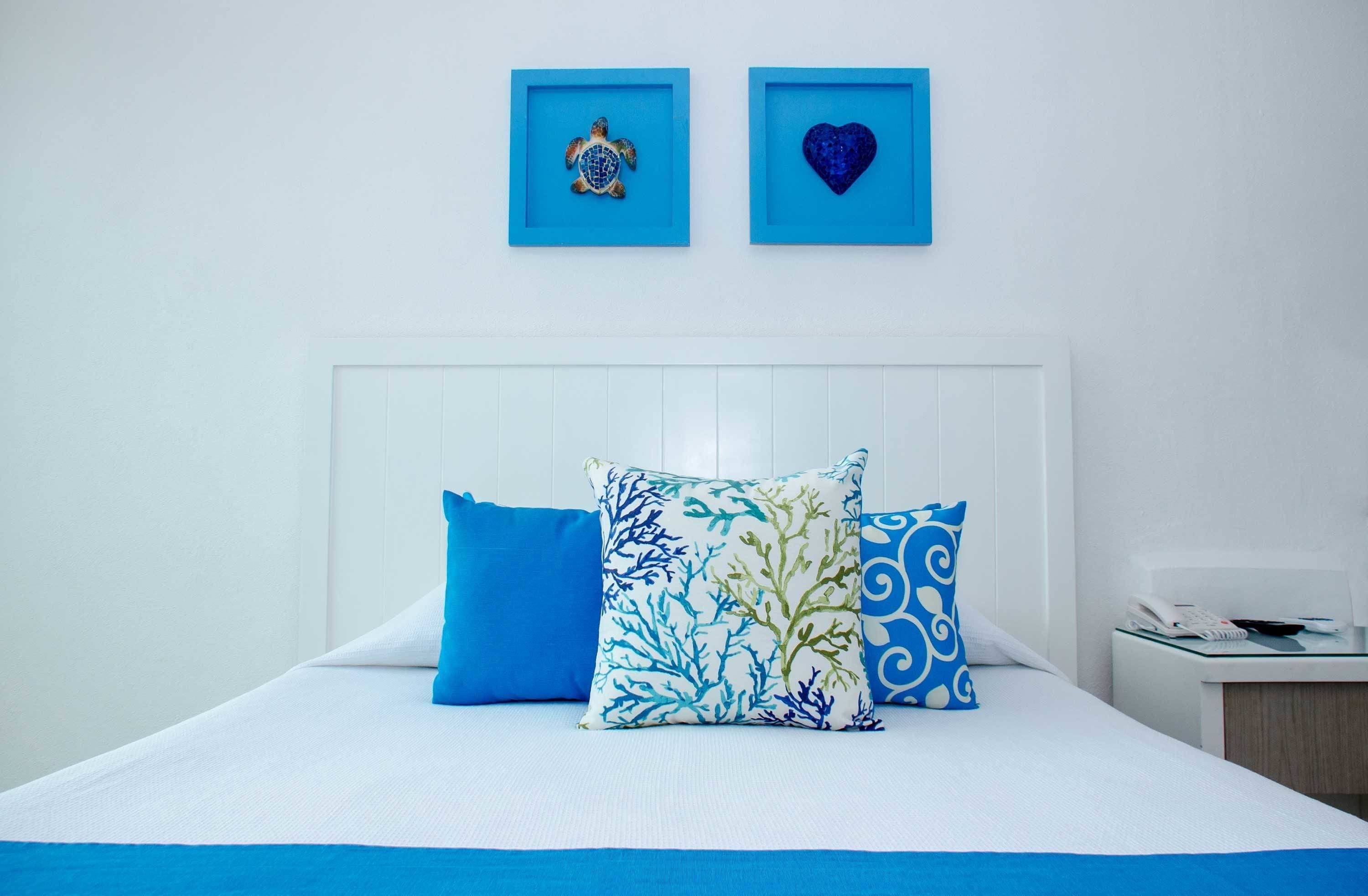 A neatly made bed with blue and white bedding, a white headboard, and decorative pillows.